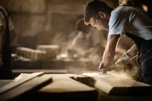 Handwerker beim Schleifen von Holz in einer staubigen Werkstatt