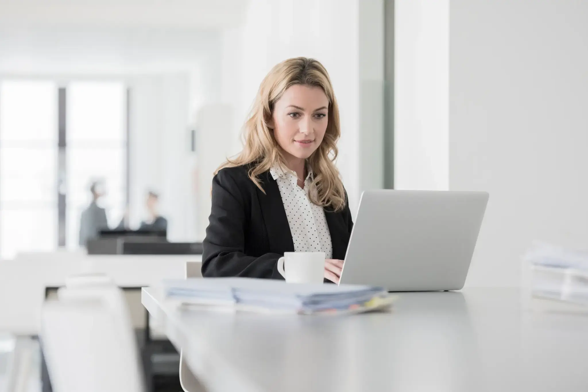 betriebshaftpflichtversicherung | Geschäftsfrau im Büro arbeitet konzentriert am Laptop und informiert sich online zur Betriebshaftpflichtversicherung