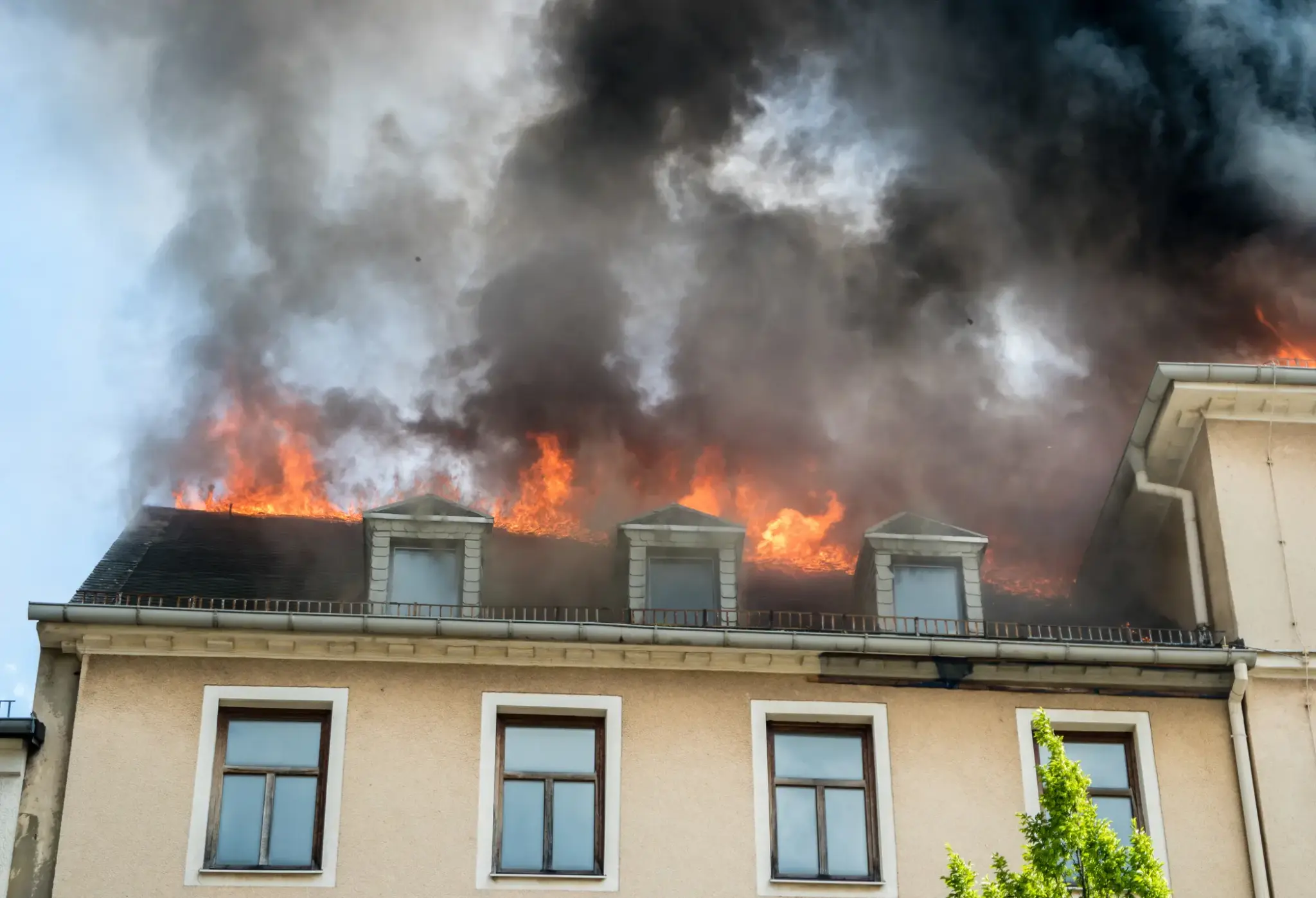 Dachgeschoss eines Wohnhauses in Flammen, dichter Rauch steigt auf