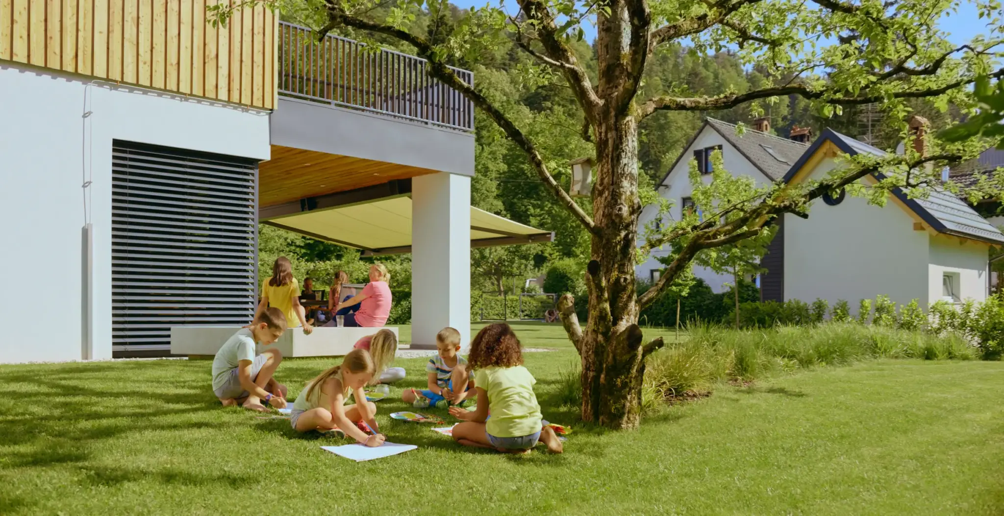 Kinder spielen im Garten eines Einfamilienhauses – Symbolbild für Sicherheit durch eine Hausversicherung.