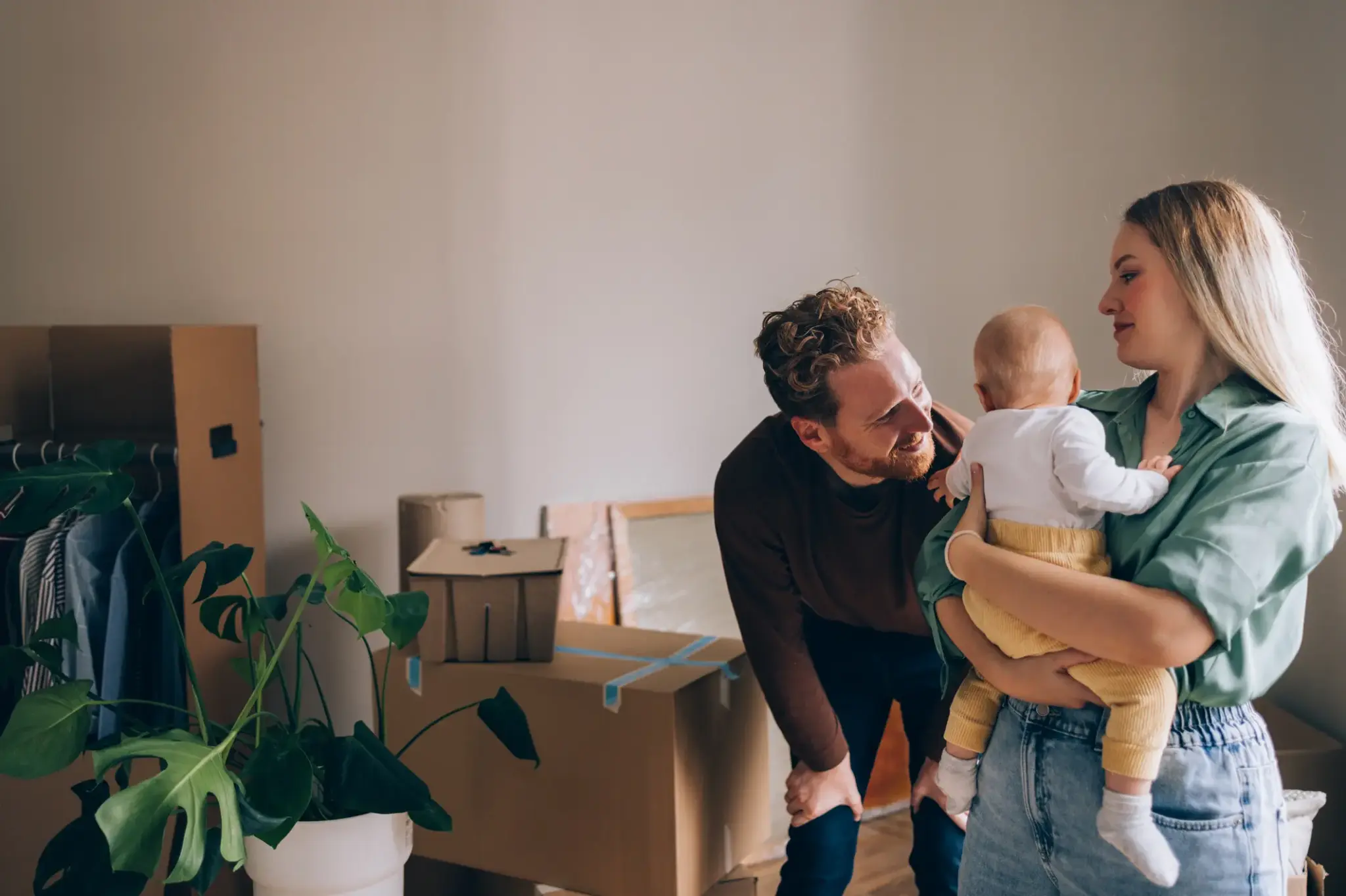 Junge Familie mit Baby beim Einzug in eine neue Wohnung – Schutz und Sicherheit durch passende Mieterversicherungen
