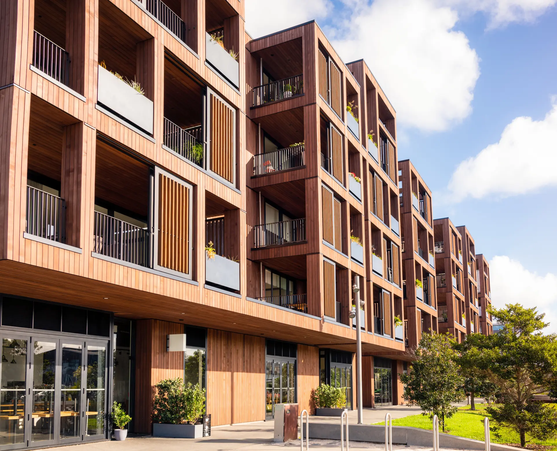 Wohnungsbaugenossenschaft | Moderne Wohnanlage einer Wohnungsbaugenossenschaft mit Holzfassade, Balkonen und begrüntem Außenbereich