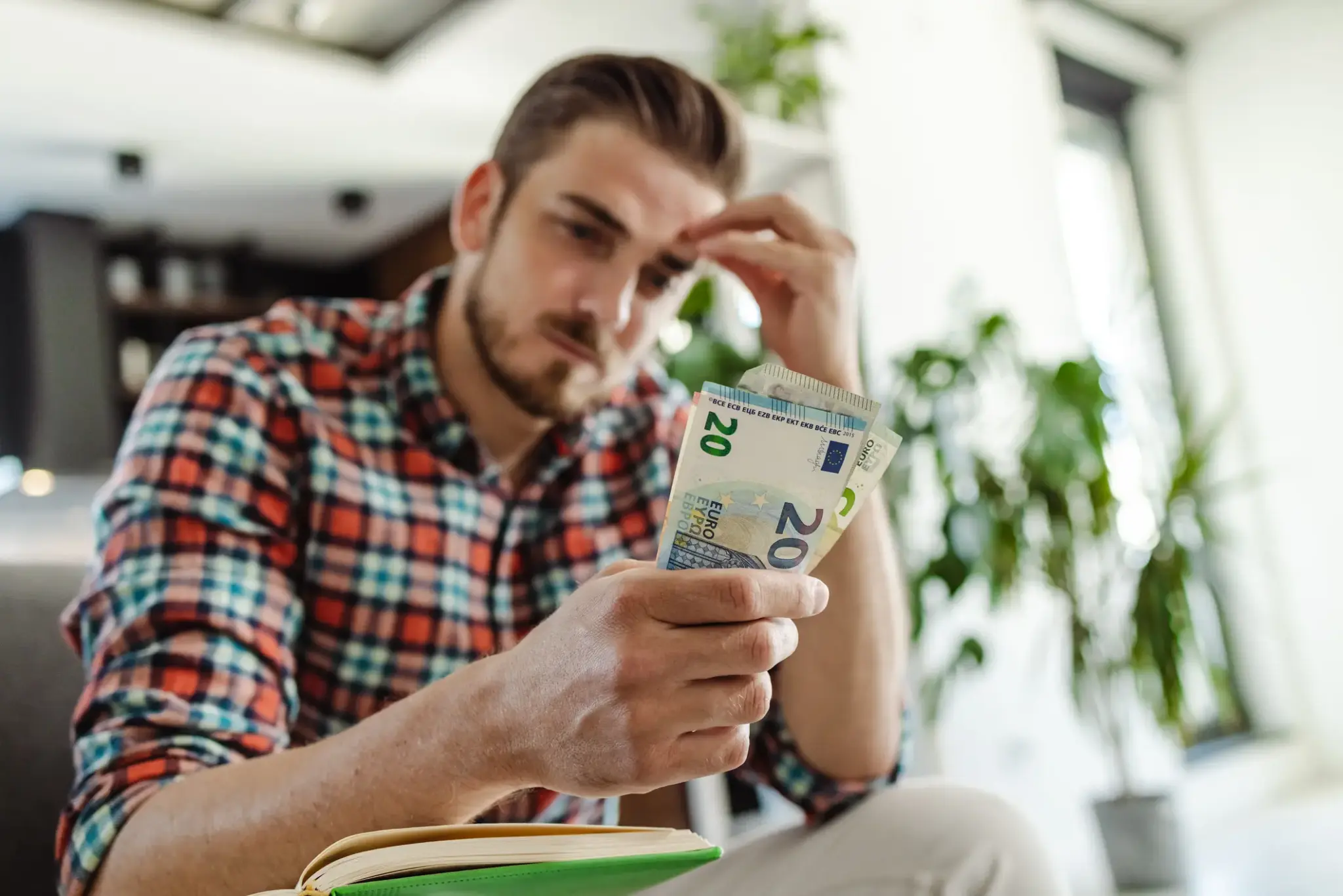 Nachdenklicher Mann zählt Geldscheine und blickt besorgt – Symbolbild für finanzielle Unsicherheit nach einem Unfall.