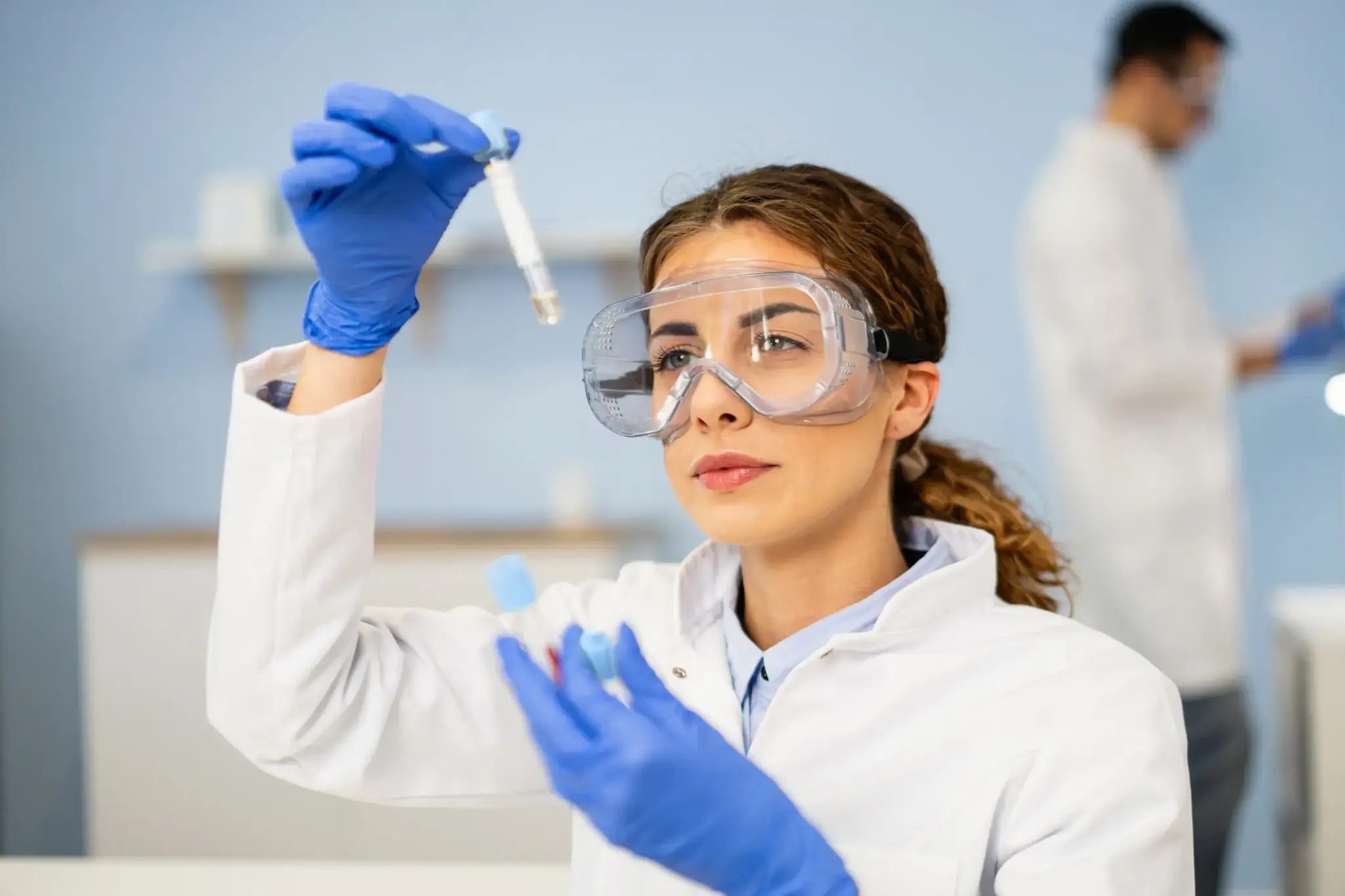 Wissenschaftlerin im Labor mit Schutzbrille analysiert eine Blutprobe – steht symbolisch für den Pantum Detect Früherkennungstest.