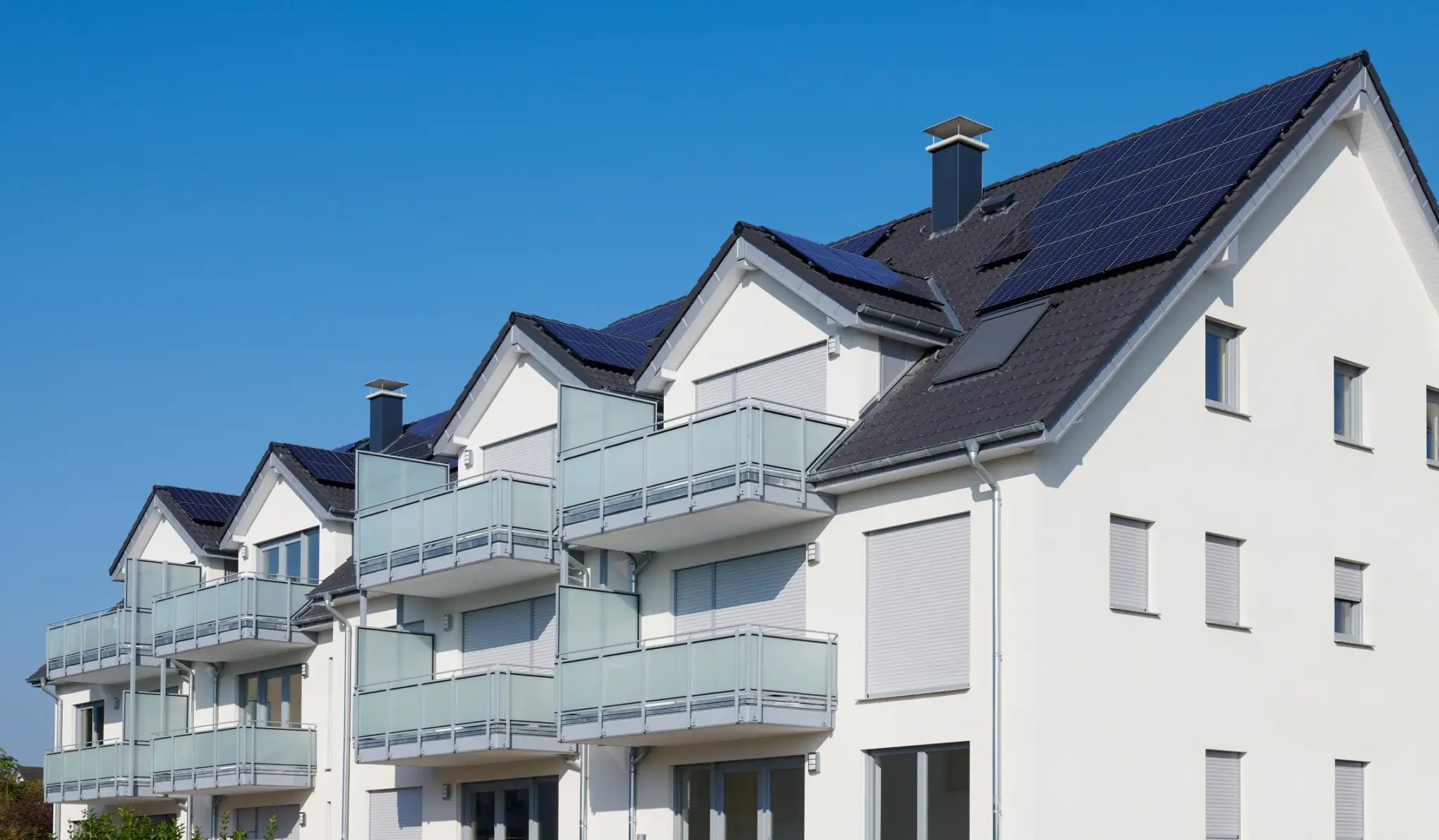 Moderne Mehrfamilienhäuser mit Balkonen und Solaranlagen auf dem Dach – Symbolbild für Immobilien und nachhaltige Wohngebäude.