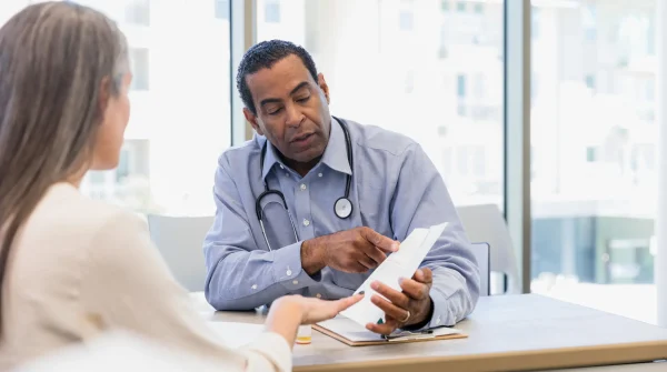 Arzt erklärt einer Patientin ein Dokument – Symbolbild für medizinische Beratung und Absicherung über eine Auslandskrankenversicherung.