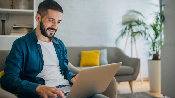 Mann sitzt entspannt auf dem Sofa und arbeitet mit einem Laptop – Symbolbild für digitale Altersvorsorge mit der Basisrente.
