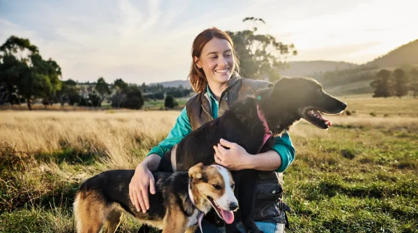 Hundehalterin auf Wiese mit zwei Hunden – Symbolbild für verantwortungsvolle Tierhaltung und Betriebshaftpflicht im Hundebereich.