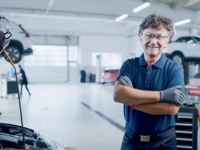 Gut gelaunter Kfz-Sachverständiger in moderner Werkstatt – Symbol für die Absicherung durch eine Sachverständigen-Versicherung