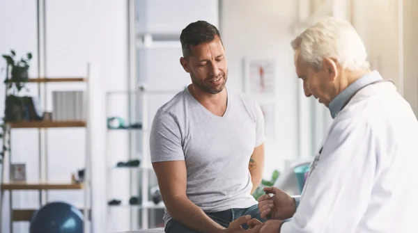 Arzt spricht mit einem männlichen Patienten in moderner Praxis – Beratung zur gesetzlichen Krankenversicherung